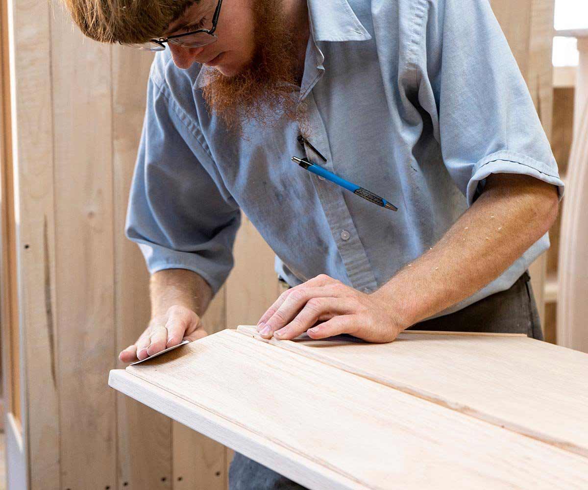 An Amish craftsman sanding part of a custom cabinet